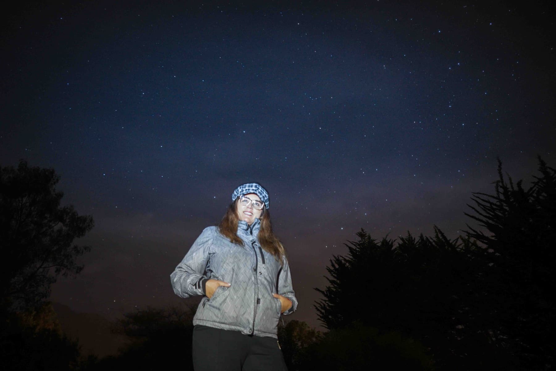 Una visitante con gorro y lentes posa bajo el cielo estrellado del Molle.